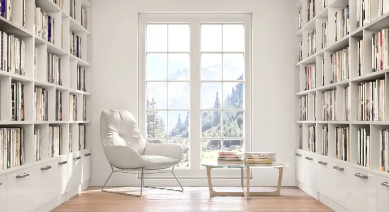 A modern home office featuring built-in bookshelves and large windows.