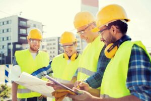 A team of contractors reviewing blueprints at a construction site.