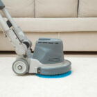 A technician using advanced cleaning equipment to restore the beauty of a plush beige carpet.