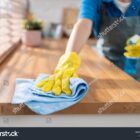 A professional cleaner wiping down kitchen surfaces in an empty, freshly painted home.