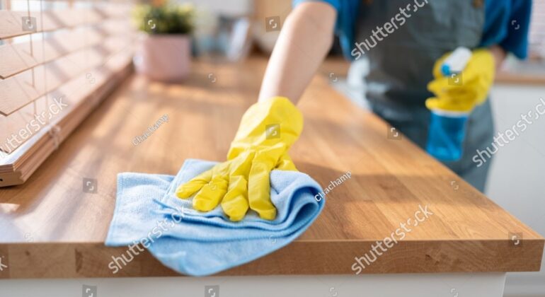 A professional cleaner wiping down kitchen surfaces in an empty, freshly painted home.